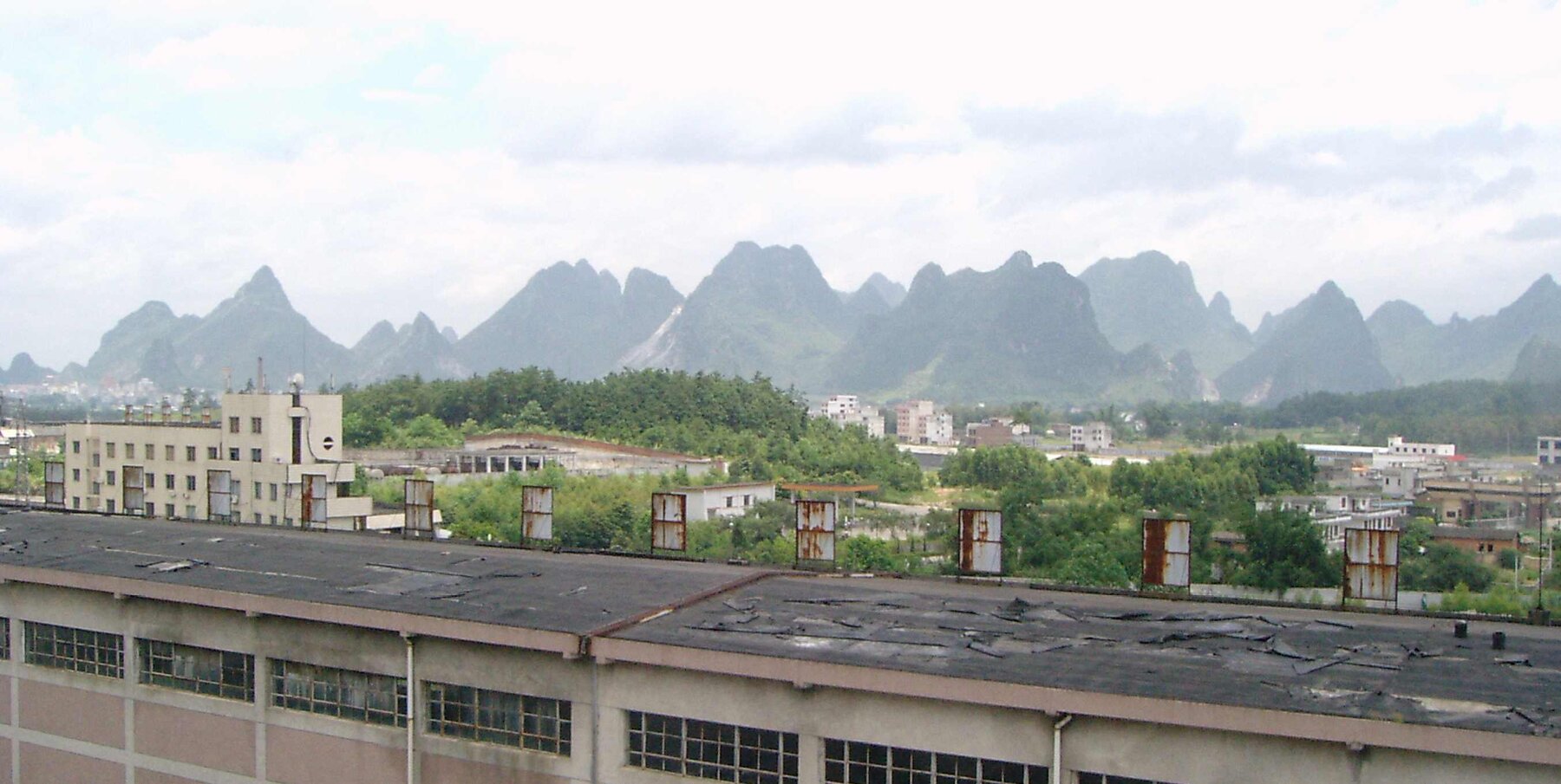 Montanhas de calcita ao fundo, com a HouDa Paper Co. em primeiro plano (Guangxi, China)